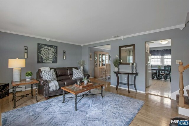 living area featuring a baseboard radiator, baseboards, crown molding, and wood finished floors