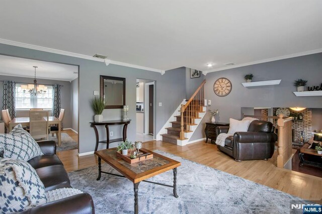 living room with baseboards, a chandelier, wood finished floors, stairway, and ornamental molding