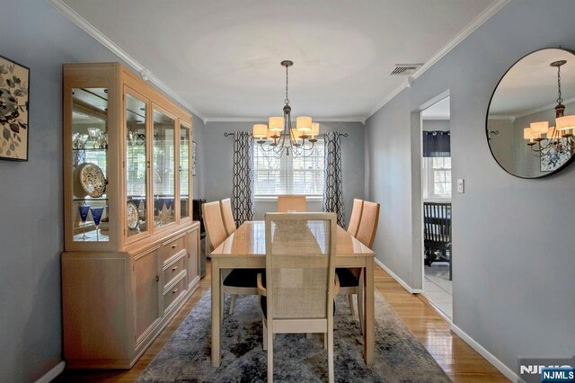 dining space featuring a chandelier, light wood-style floors, ornamental molding, baseboards, and visible vents
