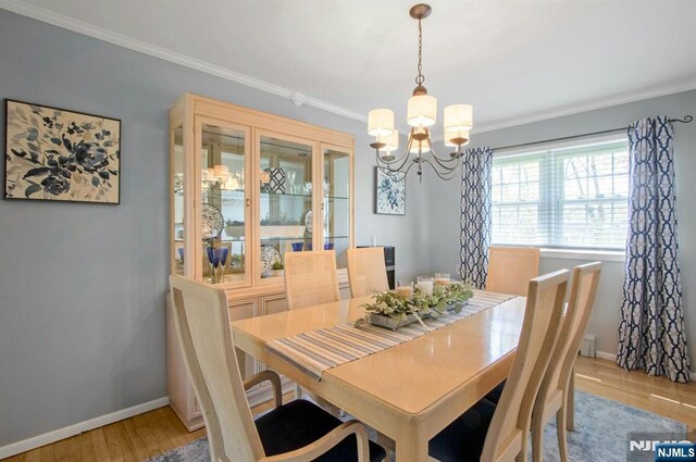 dining space featuring an inviting chandelier, crown molding, light wood finished floors, and baseboards