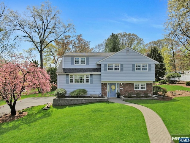 view of front of home with a shingled roof and a front lawn