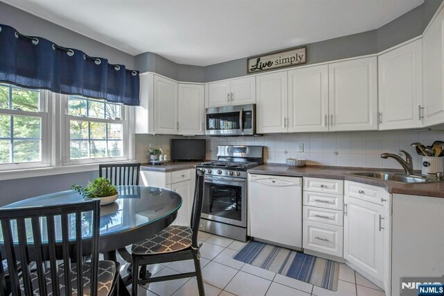 kitchen with dark countertops, a sink, stainless steel appliances, and decorative backsplash