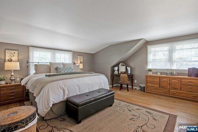 bedroom featuring baseboards, vaulted ceiling, and light wood-style flooring