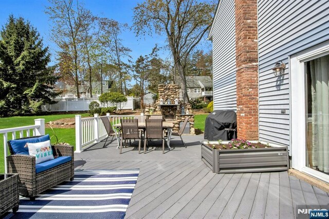 deck featuring fence, a lawn, outdoor dining area, and area for grilling