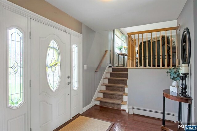 foyer with stairs, baseboard heating, wood finished floors, and baseboards