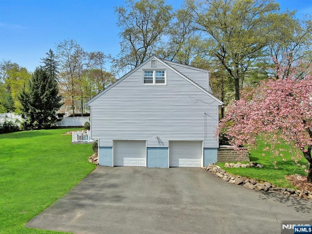 view of side of home featuring central AC unit, aphalt driveway, a yard, and a garage