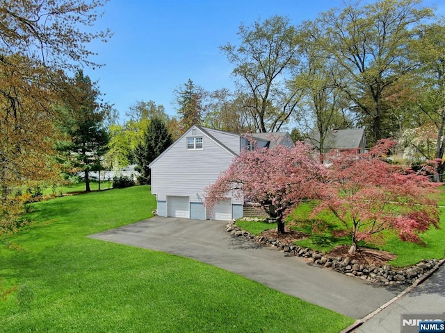 view of side of home with a lawn, driveway, and a garage