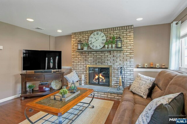 living room featuring visible vents, baseboards, recessed lighting, a fireplace, and wood finished floors