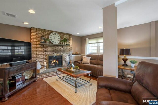 living room featuring recessed lighting, wood finished floors, visible vents, a fireplace, and a baseboard radiator