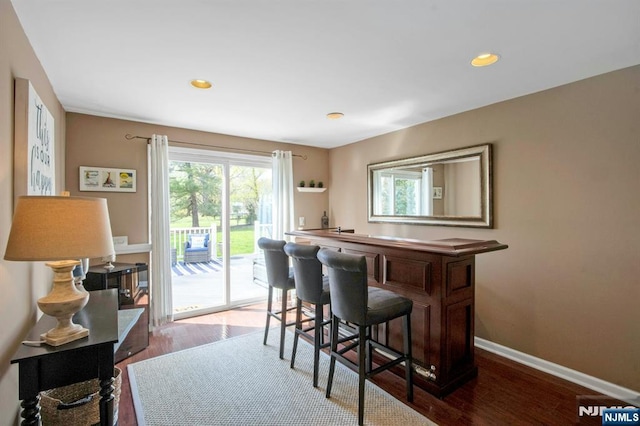bar featuring baseboards, wood finished floors, and recessed lighting