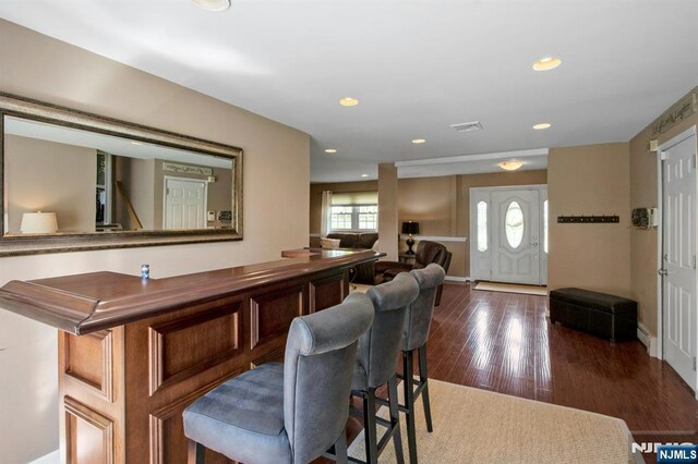bar with recessed lighting, wood finished floors, baseboards, visible vents, and a dry bar