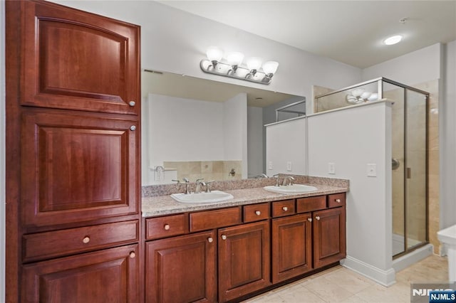bathroom with a stall shower, tile patterned flooring, double vanity, and baseboards