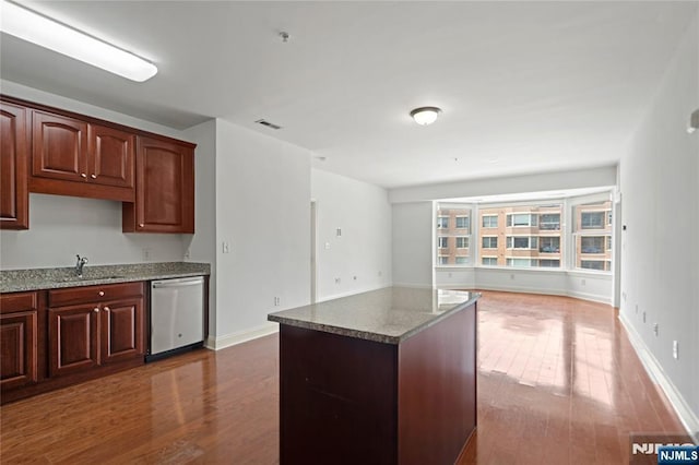kitchen featuring stainless steel dishwasher, dark wood-style flooring, open floor plan, and stone countertops