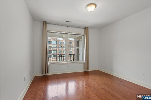spare room featuring wood finished floors and baseboards