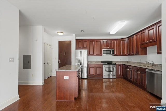 kitchen featuring stainless steel appliances, a sink, dark wood finished floors, and a center island