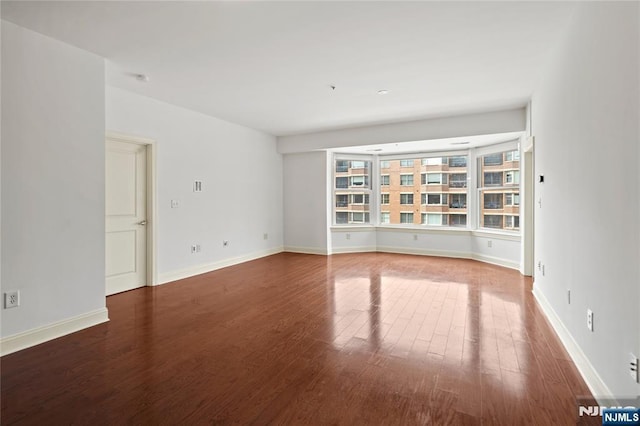 spare room featuring wood finished floors and baseboards