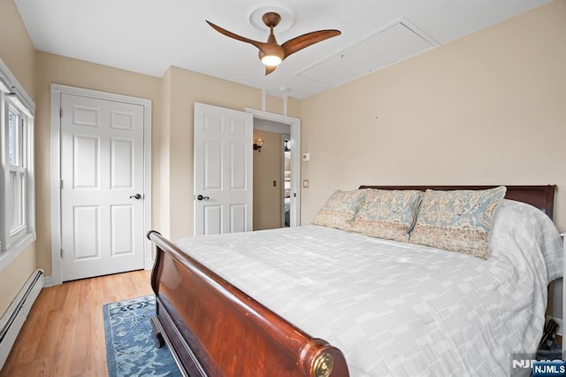 bedroom with attic access, light wood-type flooring, a baseboard heating unit, and ceiling fan