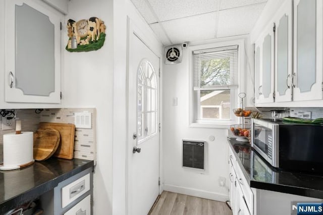 kitchen featuring decorative backsplash, dark countertops, stainless steel microwave, heating unit, and a drop ceiling