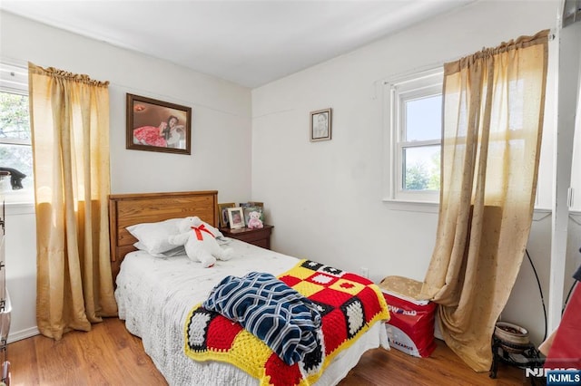 bedroom with multiple windows and wood finished floors