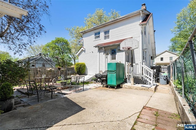 rear view of house featuring a chimney, a fenced backyard, and a patio area
