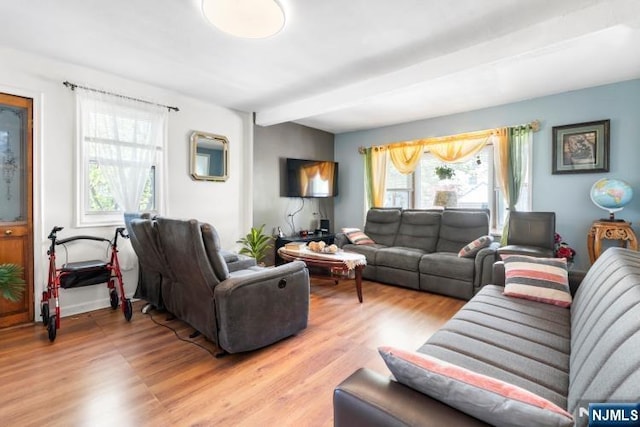 living area featuring plenty of natural light, beam ceiling, and light wood-style floors
