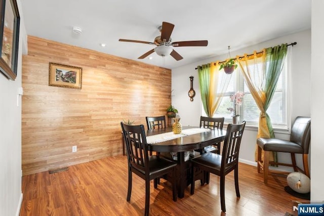 dining space featuring recessed lighting, a ceiling fan, wood finished floors, and wooden walls