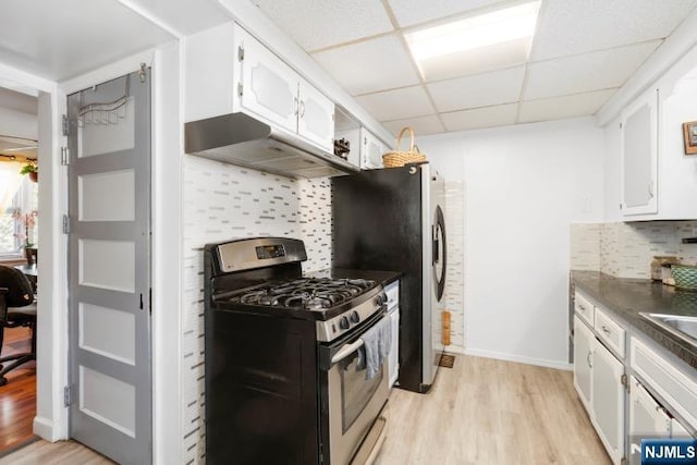 kitchen featuring stainless steel gas stove, dark countertops, a drop ceiling, white cabinets, and light wood-style flooring