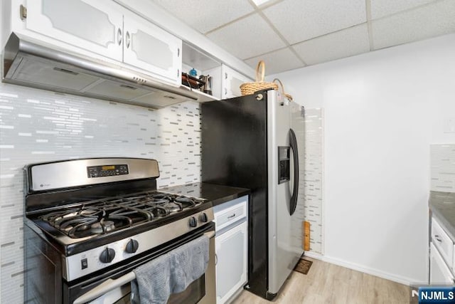 kitchen with a drop ceiling, white cabinets, light wood finished floors, exhaust hood, and stainless steel appliances