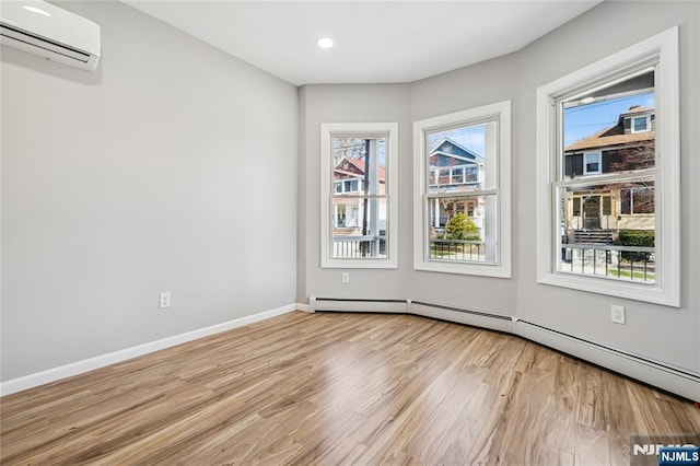 unfurnished room with light wood finished floors, an AC wall unit, baseboards, recessed lighting, and a baseboard radiator