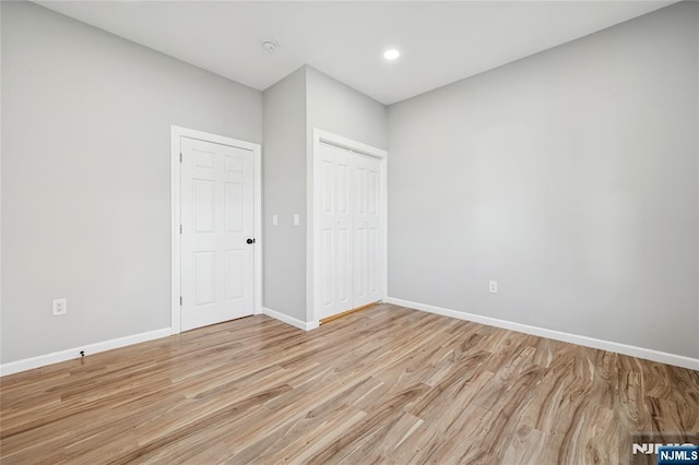 unfurnished bedroom featuring recessed lighting, baseboards, light wood finished floors, and a closet