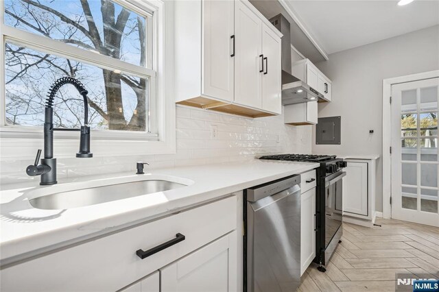 kitchen featuring backsplash, light countertops, dishwasher, a sink, and gas range
