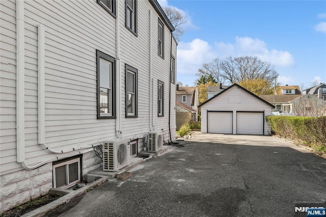 view of side of home featuring an outdoor structure, ac unit, and a garage