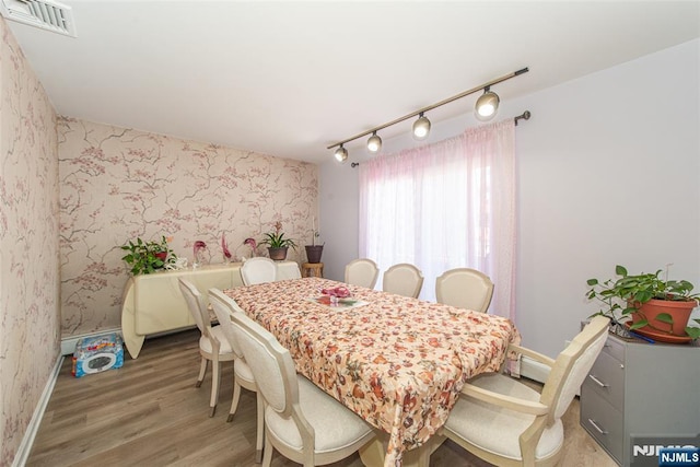 dining area featuring light wood finished floors, wallpapered walls, and visible vents