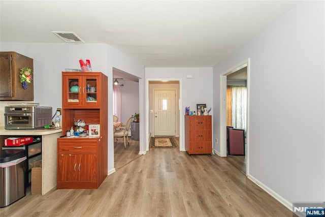 corridor featuring baseboards, visible vents, and light wood finished floors