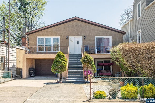view of front of home with driveway, brick siding, and stairs