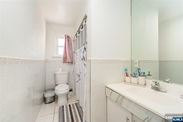 full bath featuring tile walls, a wainscoted wall, tile patterned flooring, and toilet