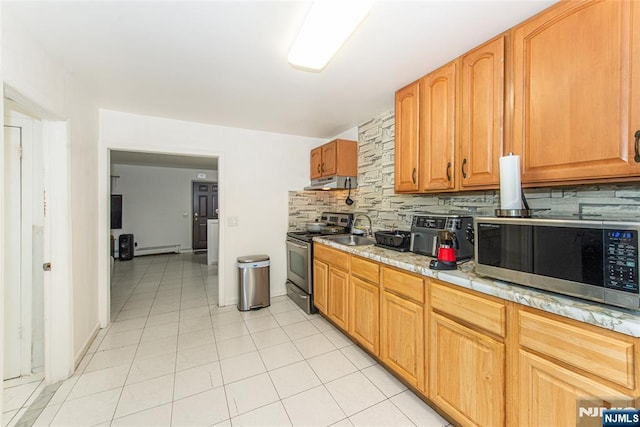 kitchen featuring tasteful backsplash, a baseboard heating unit, light tile patterned flooring, stainless steel appliances, and under cabinet range hood