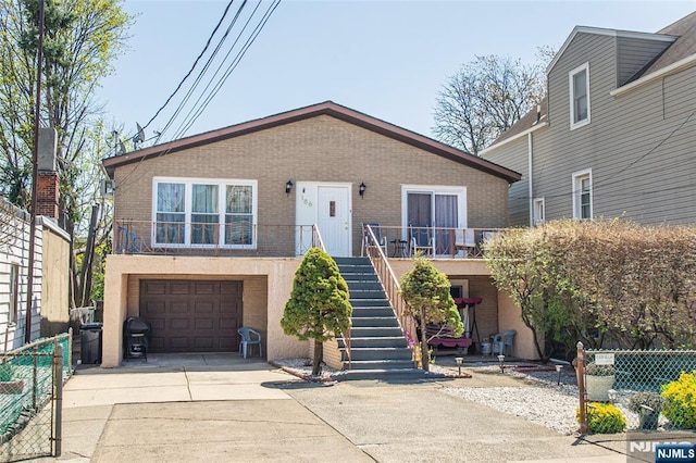 view of front of property featuring concrete driveway, fence, brick siding, an attached garage, and stairway