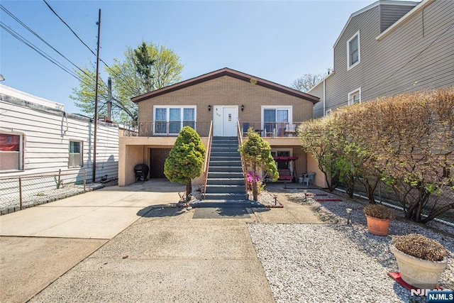 view of front of house with a garage, driveway, brick siding, and stairway
