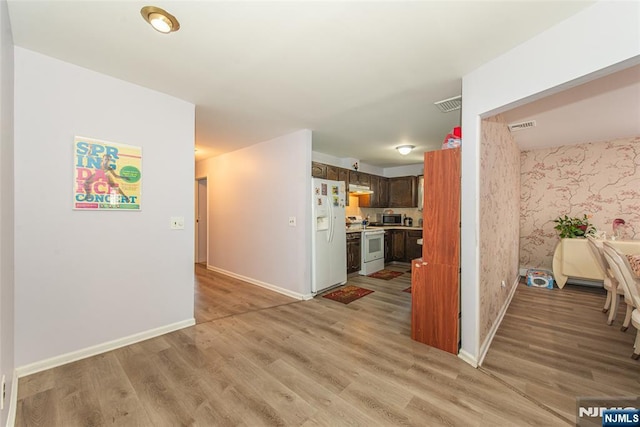 kitchen with light wood finished floors, light countertops, visible vents, white appliances, and baseboards