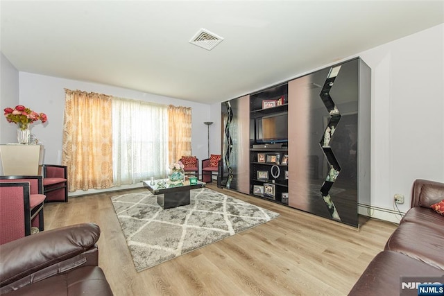 living room with a baseboard radiator, wood finished floors, and visible vents