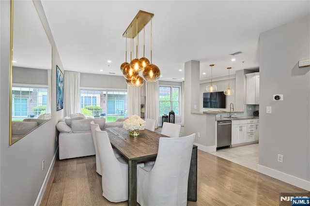 dining space with baseboards, visible vents, and light wood-style flooring