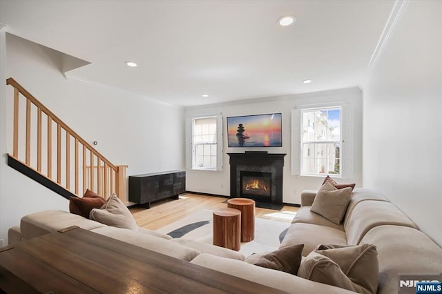 living room featuring light wood finished floors, a fireplace, recessed lighting, and crown molding