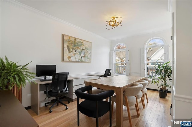 office space featuring light wood-style flooring, crown molding, and an inviting chandelier