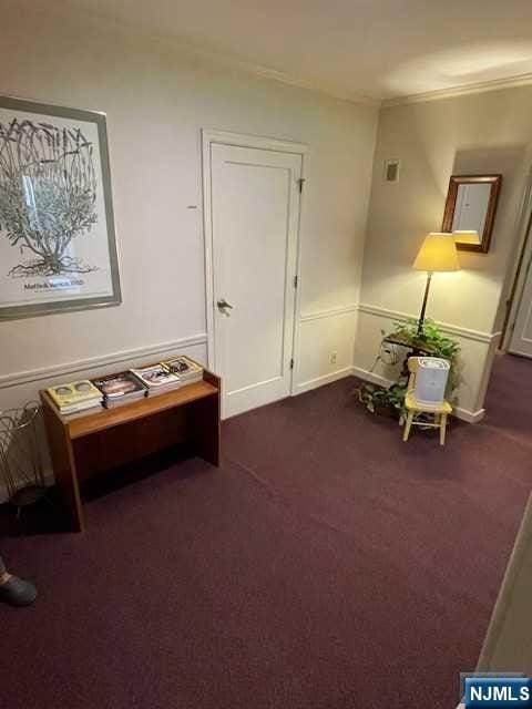 sitting room featuring dark carpet, baseboards, and crown molding