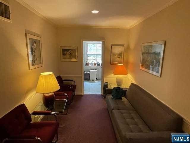 living area featuring crown molding, carpet, and visible vents