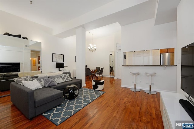 living room featuring a chandelier, wood finished floors, a high ceiling, and baseboards