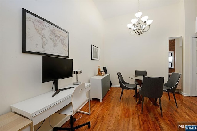 dining room featuring a chandelier, high vaulted ceiling, light wood-style floors, an office area, and baseboards
