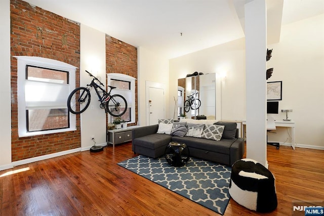 living room with baseboards, wood finished floors, a high ceiling, and a fireplace