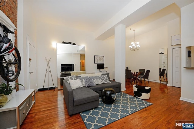 living room with a chandelier, dark wood-type flooring, a towering ceiling, and baseboards
